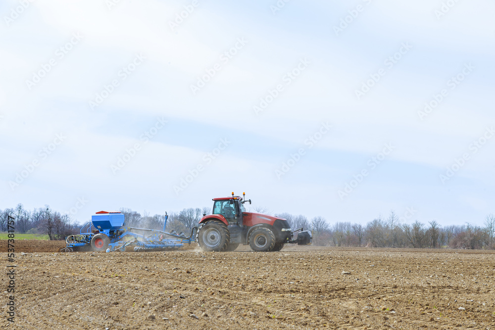 Obraz premium Agricultural tractor sows seeds in the field. Seeding equipment is working on the farmer's field.