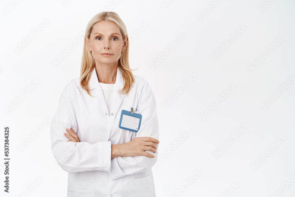 Smiling mature dermatologist, female docor, looking confident, ready to help patients, stands over white background Smiling mature dermatologist, female docor, looking confident, ready to help patients, stands over white background
