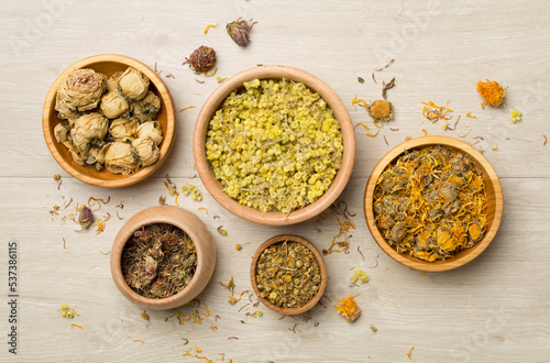 Different herbs in bowls on wooden background, top view