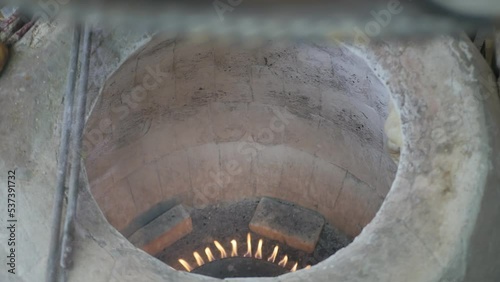 top view the hand of the male baker sends two bread pita or matnakash to the tonir on a shrink pillow, gluing the dough to the wall of the tandoor with a swing of his hand. National pastries photo
