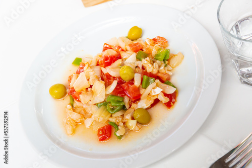 Colorful sliced codfish salad with fresh tomatoes, green pepper, onion and olives. Catalan cuisine