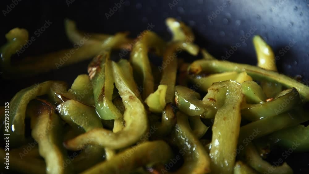 Beautiful green peppers are fried in a frying pan on an olii. Healthy food, fried vegetables.