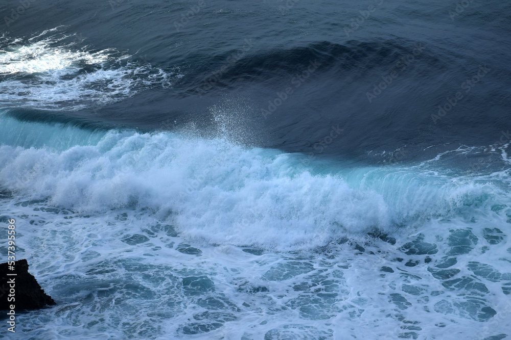 The waves crashing in the ocean, with a bluish tint at Drini Beach, Gunungkidul, Yogyakarta