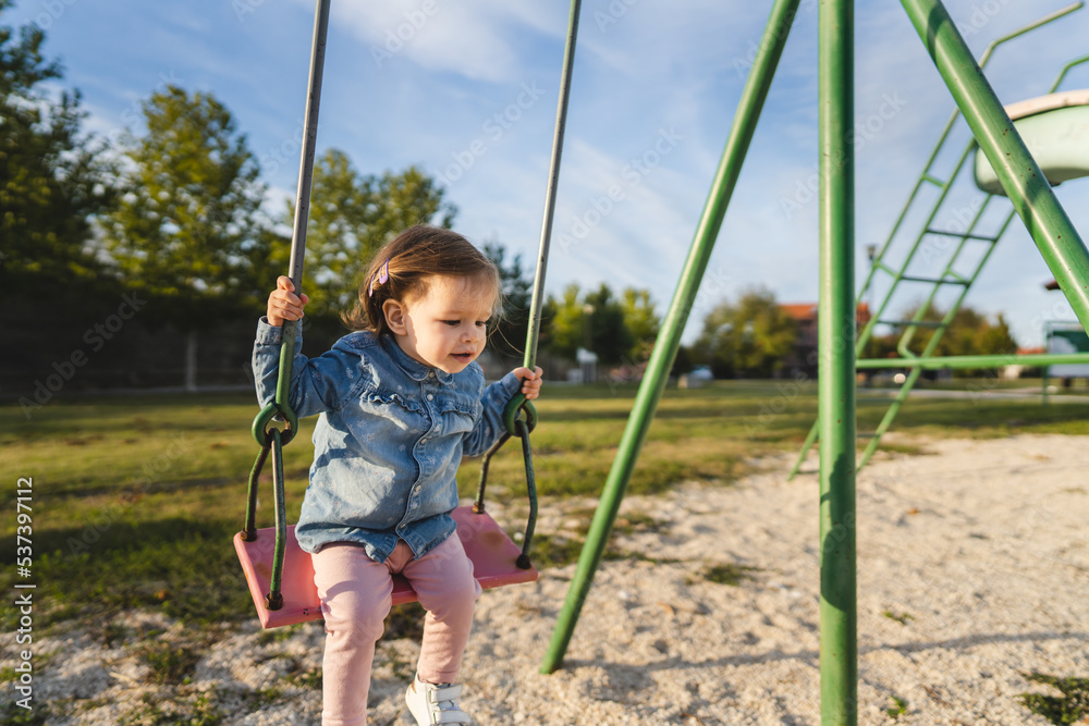 small caucasian child female toddler girl on swing in park swinging small caucasian child female toddler girl on swing in park swinging
