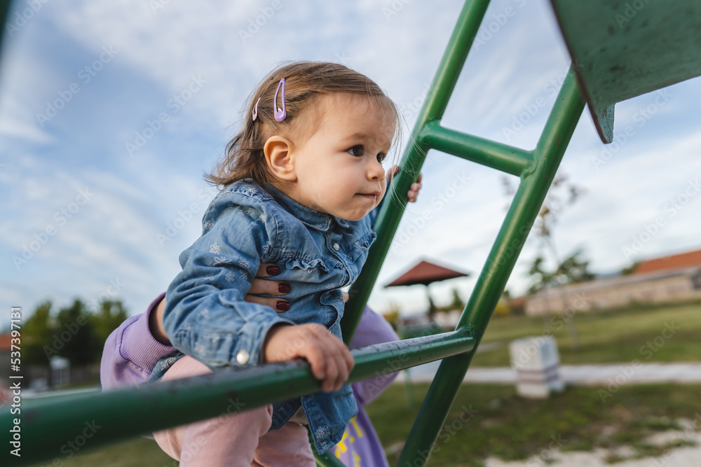 One girl small caucasian child female toddler 18 months old having fun in park on the slide in day childhood and growing up concept copy space climbing up development One girl small caucasian child female toddler 18 months old having fun in park on the slide in day childhood and growing up concept copy space climbing up development