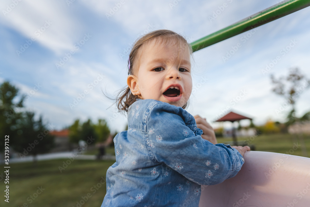 One girl small caucasian child female toddler 18 months old having fun in park on the slide in day childhood and growing up concept copy space One girl small caucasian child female toddler 18 months old having fun in park on the slide in day childhood and growing up concept copy space