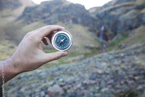Man holding a compass on a mountain background