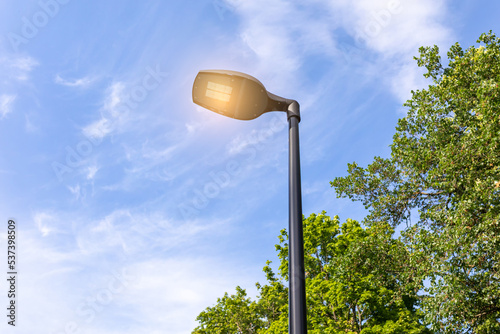 Modern lamppost with LED lamp on a summer day in a public park against the sky photo