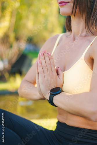 Cropped view of a woman sitting in lotus position keeping palms together. Concept of healthy lifestyle and relaxation. Youth lifestyle. Training workout.