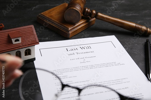 Last will and testament near house model, gavel on black table photo