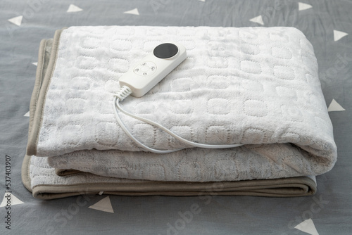 folded electric blanket with controller on the bed at horizontal composition