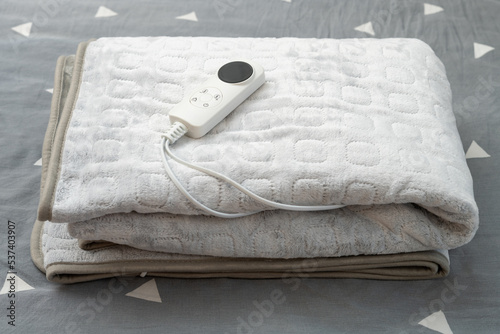 folded electric blanket with controller on the bed at horizontal composition photo