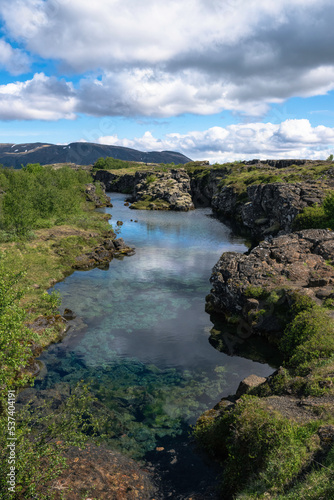 Clouds reflected in glacial water filling a fissure between tectonic plates in Thingvellir National Park, Iceland