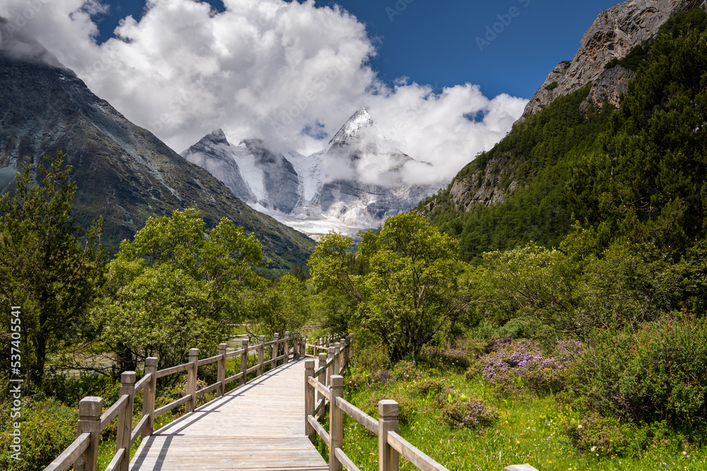Beautiful sunny day with mt. Chenrezig and wooden walkway in Yading national level reserve, Daocheng, Sichuan Province, China.