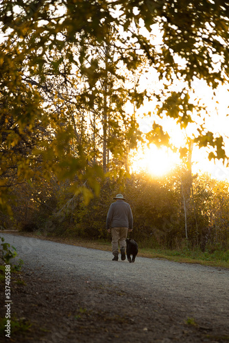 Autumn portrait of a middle aged man walking his dog at a dog park. This was taken in the evening as the sun was setting. 