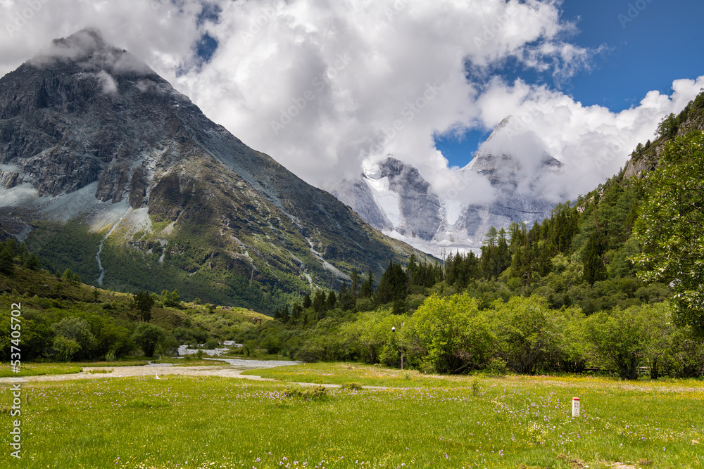 The green meadows and snow mountains in Yading and Daocheng, the last Shangri-La, in Sichuan, China, shot in summer time. Horizontal image with copy space for text