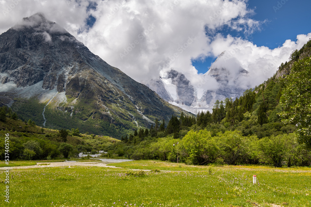 Summer scenery in Yading Nature Reserve, Daocheng county, Ganzi Tibetan Autonomous Prefecture, Sichuan province of China. Horizontal iimage, sky with clouds