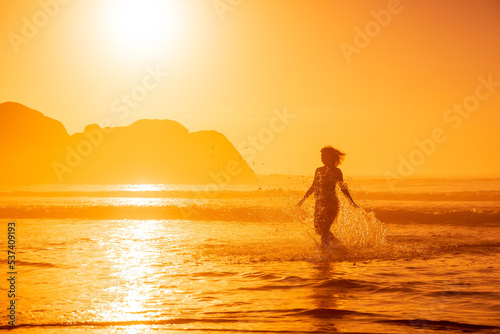 Fototapeta Naklejka Na Ścianę i Meble -  Pregnant woman walking on ocean beach at beach with sunrise or sunset