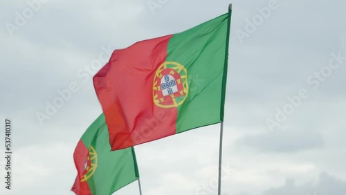 [4k] Two Portuguese flags gently waving in the wind under cloudy sky
