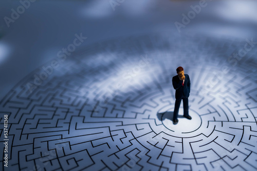 Miniature Business man thinking how to solve this problem.Business obstacle,financial,business growth concept.Business man stand on center of maze. photo