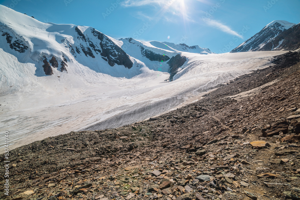 Scenic mountain landscape with large glacier in sunlight. Awesome scenery  with glacial tongue under sun in