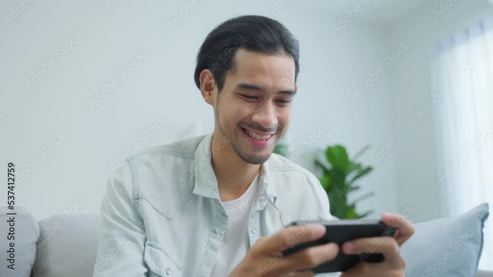 Asian young handsome man gamer play mobile game on smartphone at home. Asian young handsome man gamer play mobile game on smartphone at home.