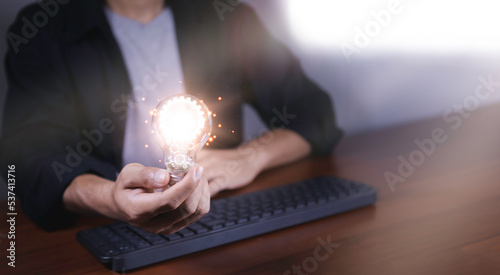 The hand of a man with a light bulb and there is a gear icon in it. Thinking differently creates inspiration and ideas.Technologies can always come from creative and different ideas.