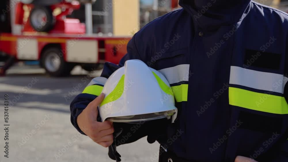 Fireman with helmet near fire engine. Concept of saving lives, heroic profession, fire safety Fireman with helmet near fire engine. Concept of saving lives, heroic profession, fire safety