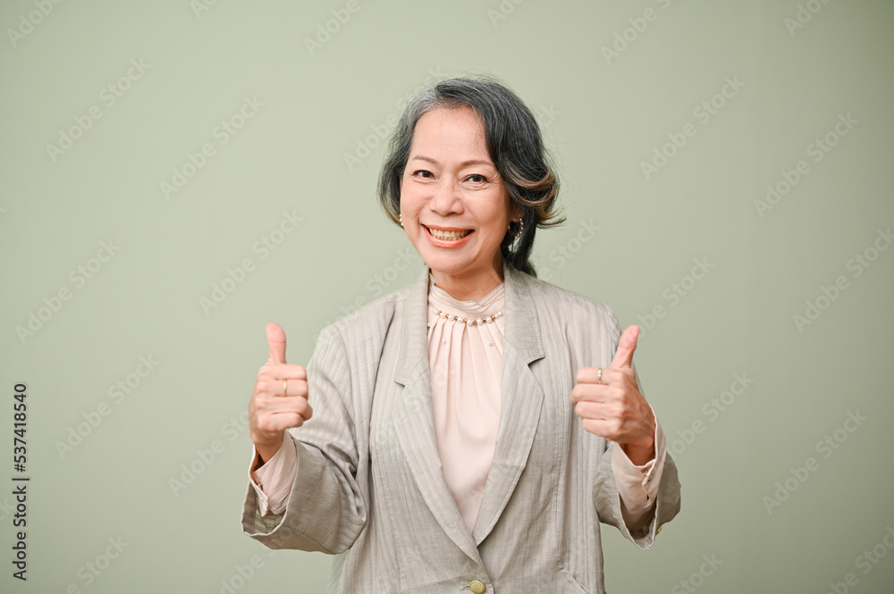Happy 60s aged-asian woman smiling and showing tumbs up, isolated background. Awesome, Excellent Happy 60s aged-asian woman smiling and showing tumbs up, isolated background. Awesome, Excellent