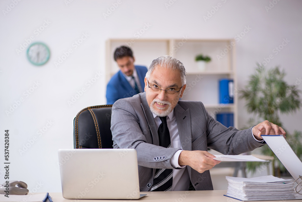 Old male boss and young male employee working in the office Old male boss and young male employee working in the office