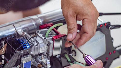 Man's hand holding the engine of an RC plane, he is repairing it.