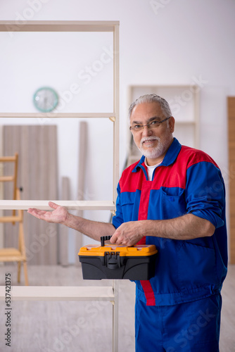 Old male carpenter working indoors