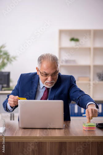 Old male employee working at workplace