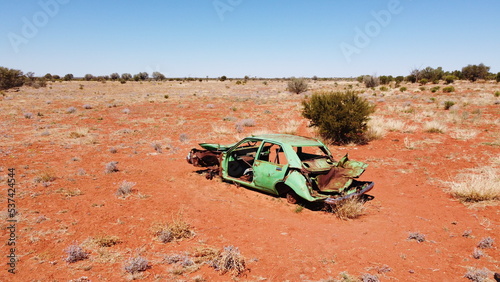 Abandonned car in the middle of the red desert in Australia. Lost car in the sand next to the road, view from the back. Northern territory.