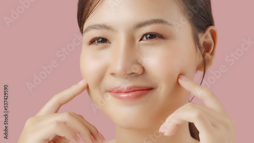 Close up portrait beauty shot of Beautiful Asian girl looking at camera isolated on pink background with copy space.