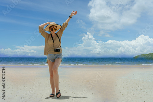 portait of woman wearing sun hat sungrasses and have camera standing on the beach with sunny day photo