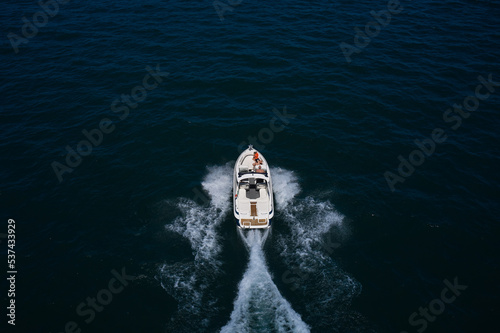 Big white motor boat movement on the water back view. Top view of the yacht in motion. White yacht in motion with people back view.