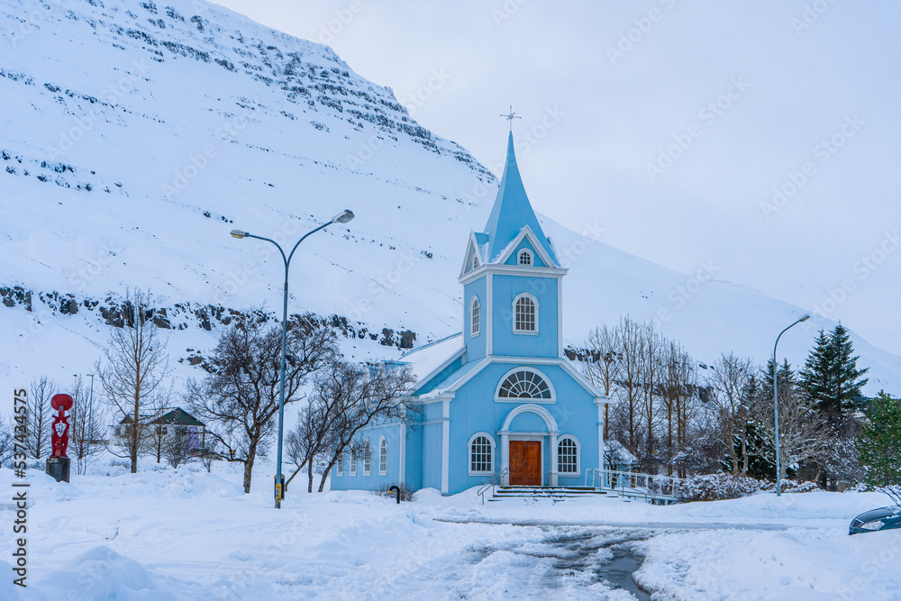 Regnboga Vegur or Rainbow Road  and Seyðisfjarðarkirkja blue wooden church  during winter evening at Seydisfjordur , Fjord towns in Eastern Coast Iceland  : 18 March 2020