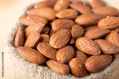 Small linen bag with almonds, close up. Macro shot of fresh tasty almond nuts in bag