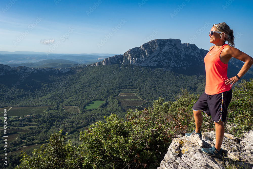 Female hiker stetching at view point while hiking the Pic saint Loup in the south of France