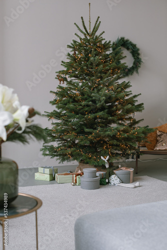 Aesthetic Christmas tree in modern home interior. Beautiful New Year tree with stylishly wrapped gifts. © Nina
