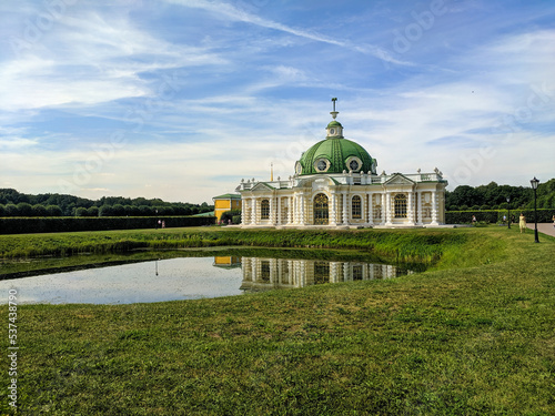 Photography Moscow, Russia - August 13, 2022: Beautiful view of the Grotto pavilion, a pond and a park area with a green lawn in the museum-estate of Kuskovo