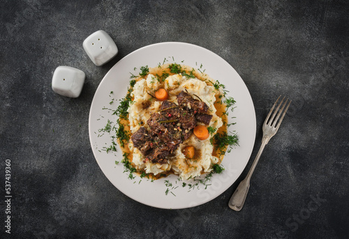 Beef cheeks with mashed potatoes on white plate.