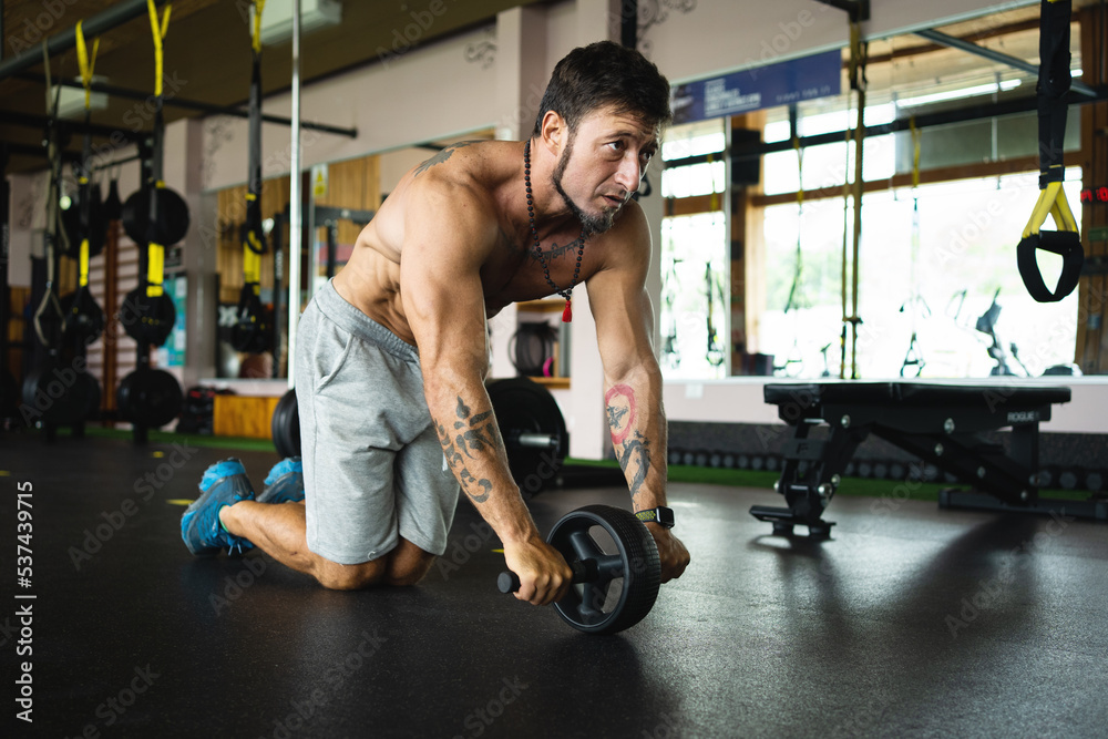 Person doing abs using a roller in the gym Person doing abs using a roller in the gym