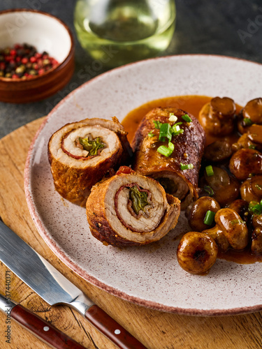 Pork roulade with pickles and bacon, served with fried mushrooms and green onions