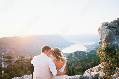 Bride and groom sit hugging on a mountain overlooking the Kotor Bay. Montenegro