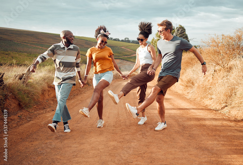 Travel, friends holding hands and dance in nature, outdoors or countryside on vacation. Happy, diversity and group smile, spending time together and dancing, celebration and having fun on sandy road.