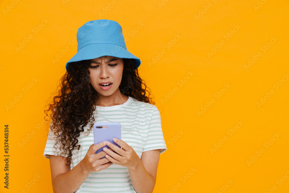 White curly woman wearing panama frowning while using cellphone White curly woman wearing panama frowning while using cellphone