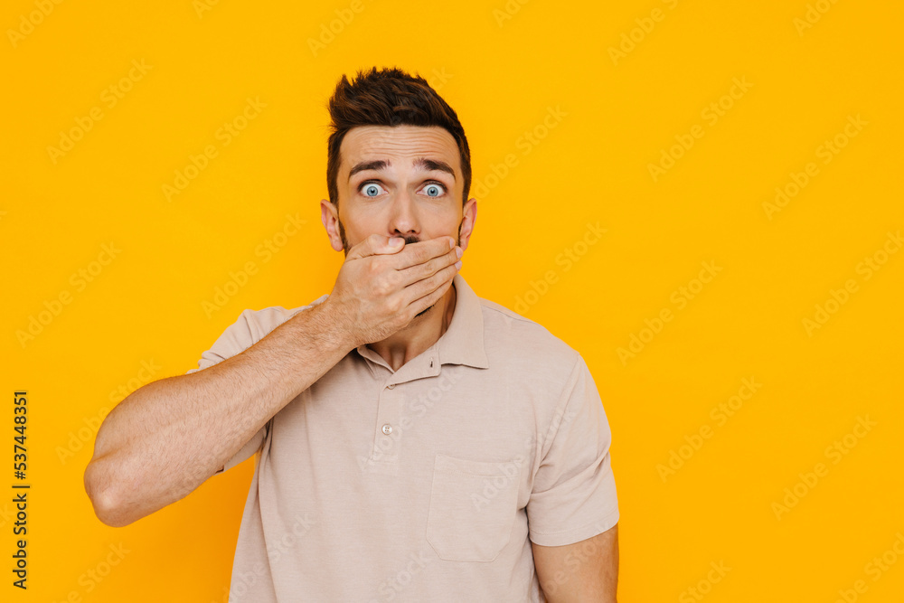 White brunette man expressing surprise while covering his mouth White brunette man expressing surprise while covering his mouth