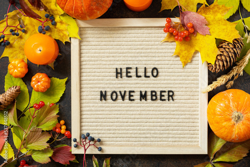 Autumn background with Hello November letters and autumn message board, pumpkins and colorful leaves. Cozy autumn mood. Fall seasons greeting card. photo